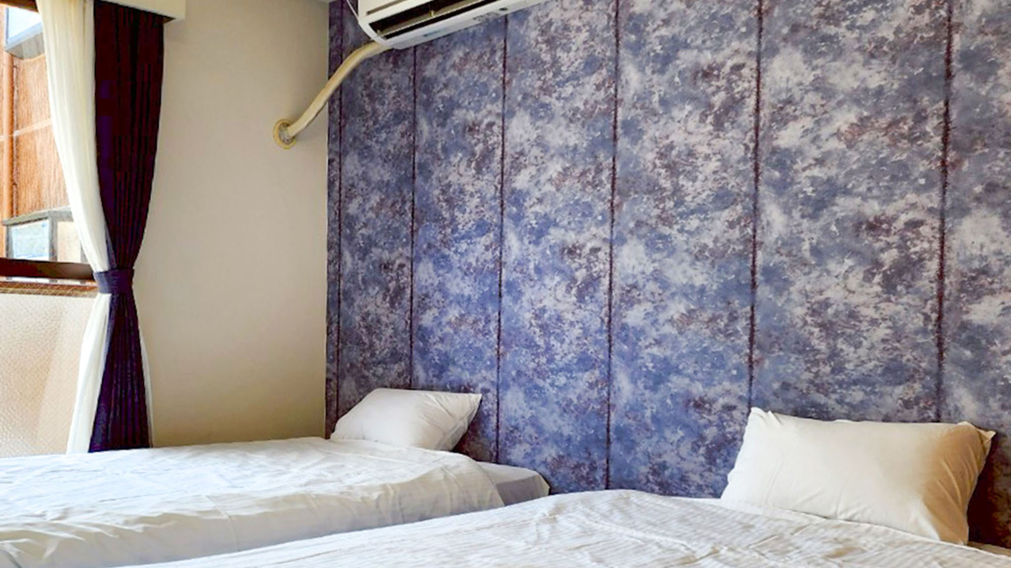 ・【203：寝室】シングルベッド2台を備えた1Kツインルーム。青い壁紙が目を引きます