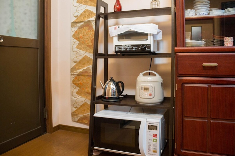 A kitchen with a rice cooker, a microwave, a...