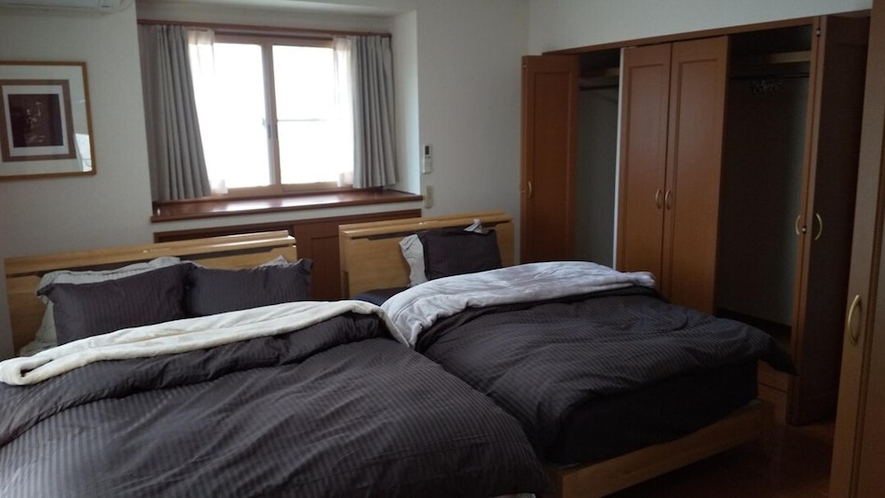 主寝室。ダブル×1、セミダブル×1のベッドとウォーキングクローゼット、ワークスペースを備えています。
