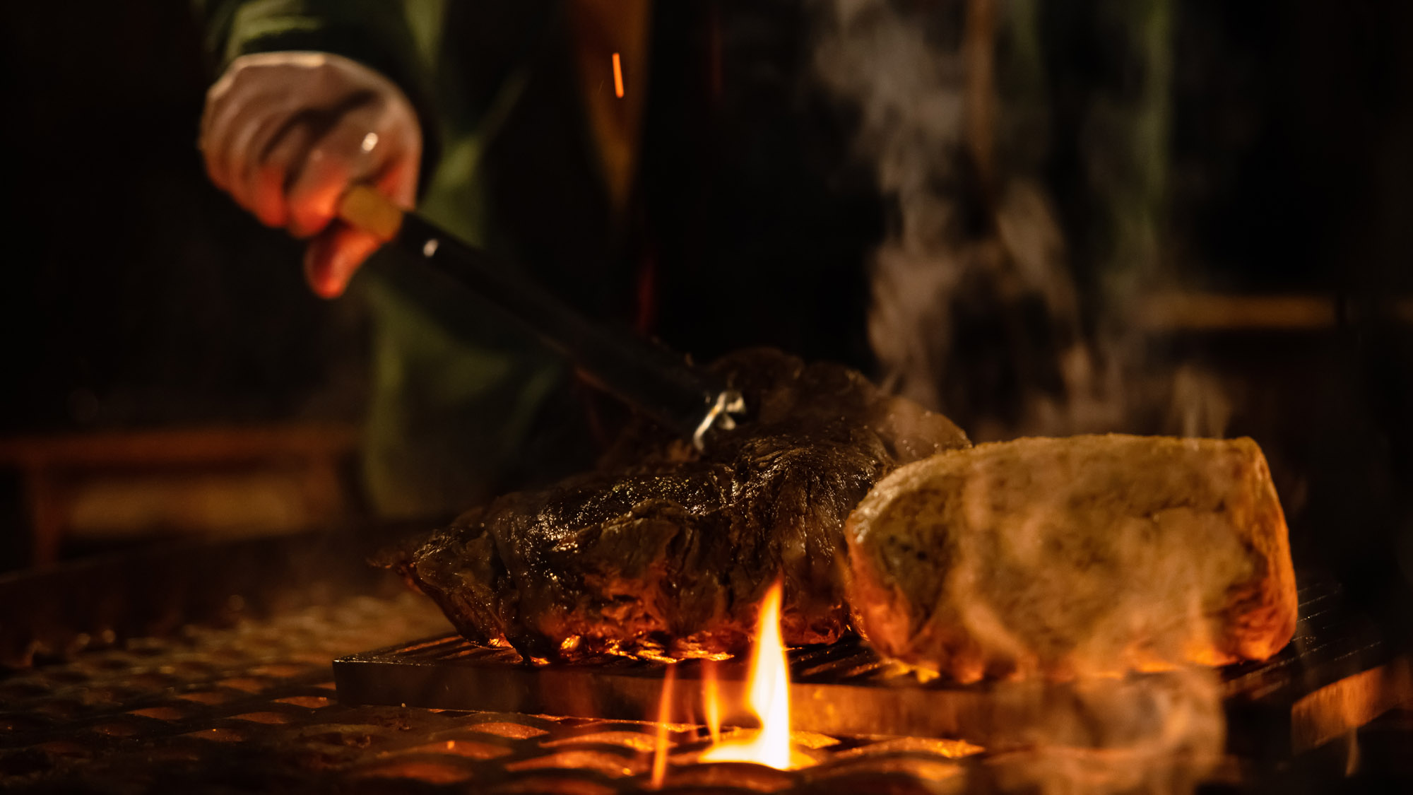 炎の上で豪快に焼き上げる塊肉、食欲をそそるシーン。