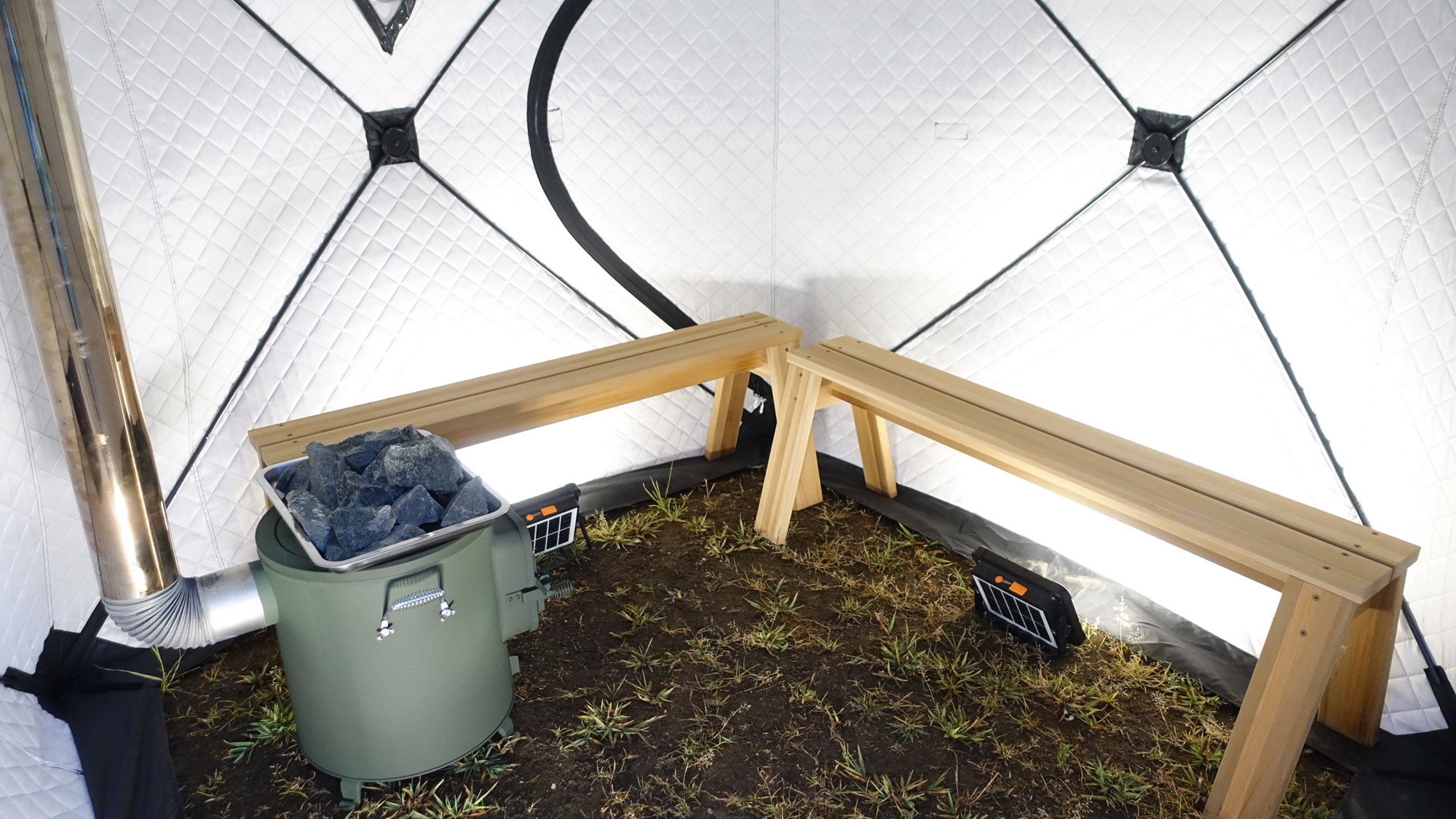 テントサウナの内部は、木のベンチとサウナストーンで本格仕様。自然と一体になれる体験。