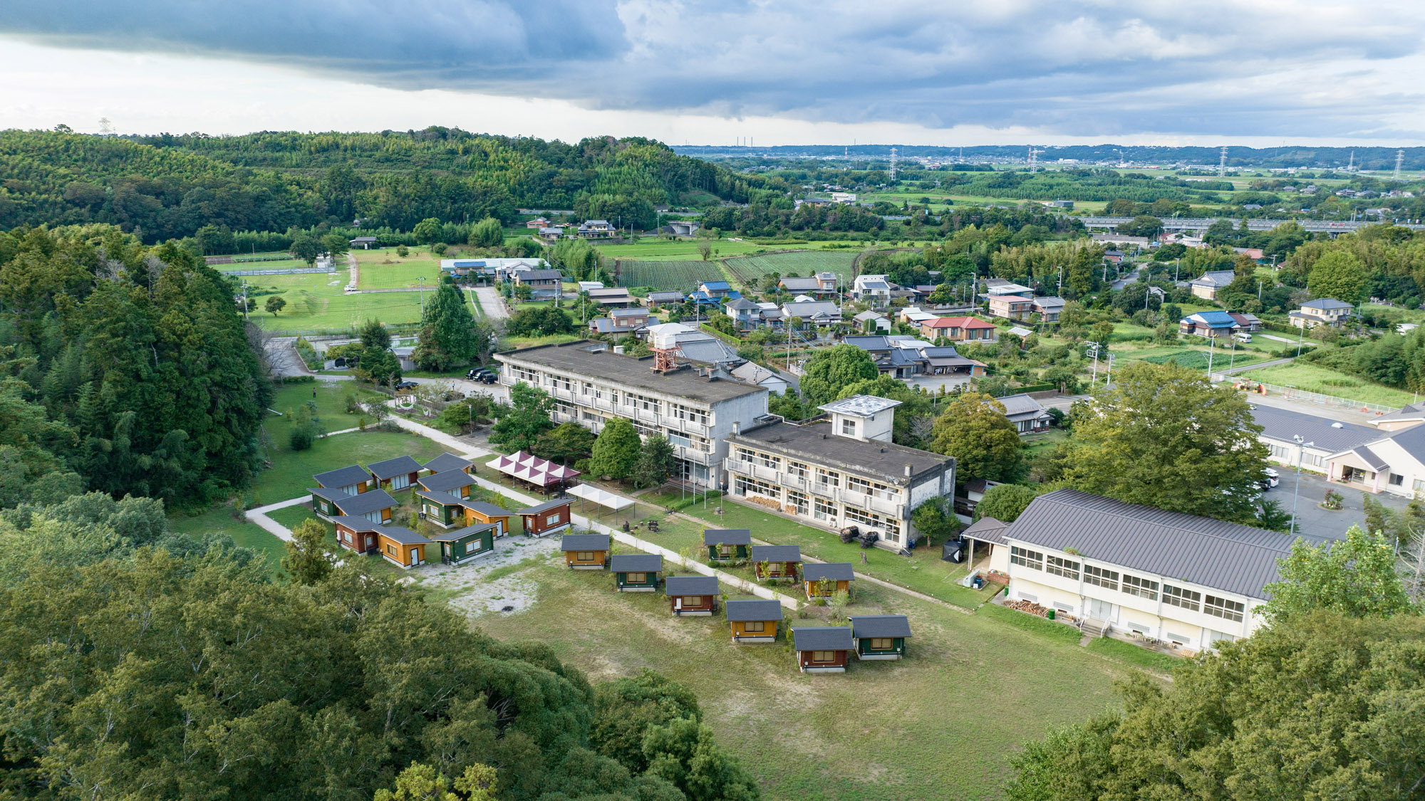 自然に囲まれた旧校舎とキャビンが並ぶ、ETOWA木更津の全景。
