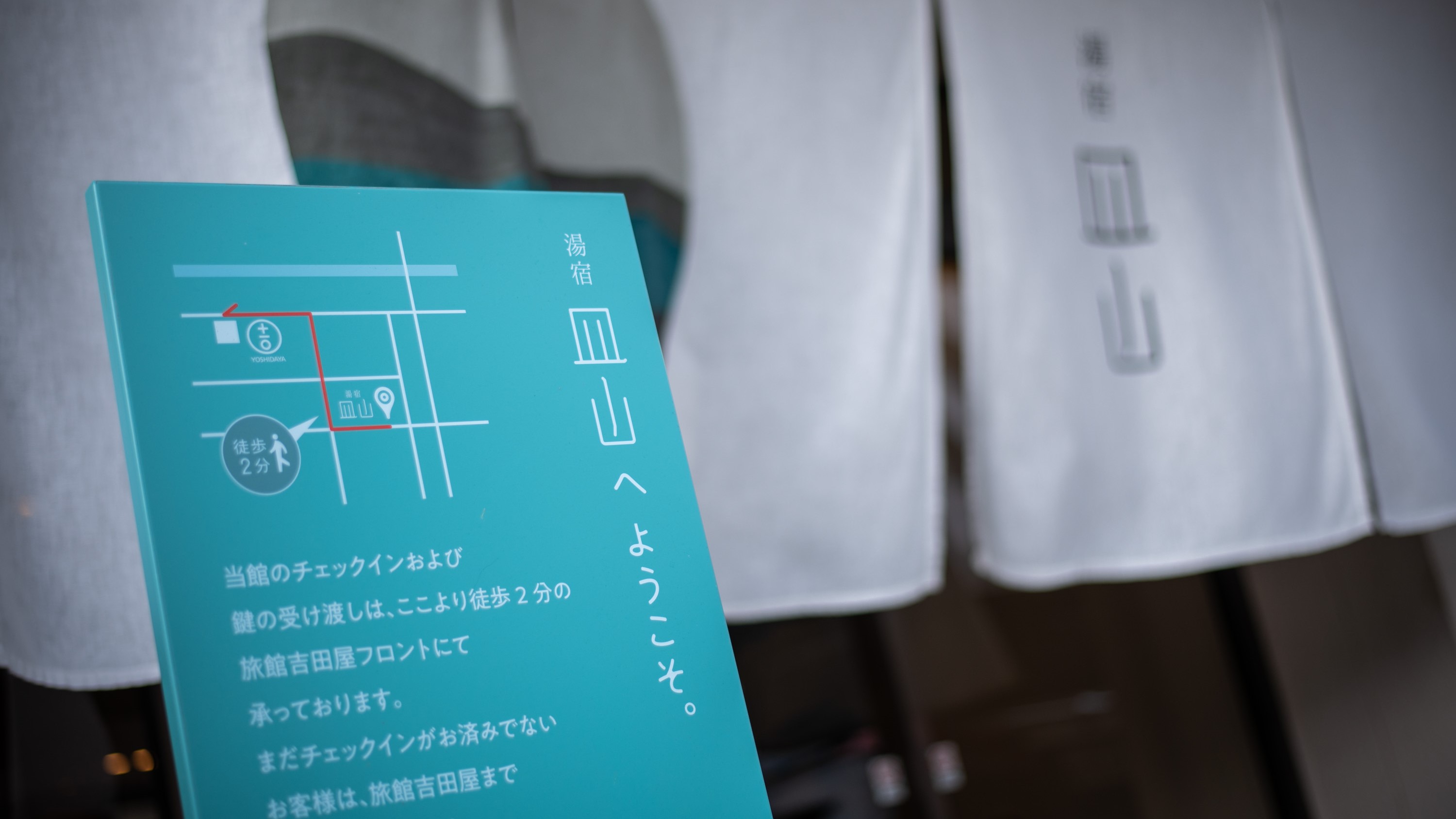 正面玄関にはチェック時の案内を設けています。まずは、徒歩数分の旅館吉田屋にて受付をお願いします♪