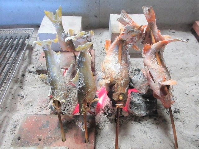 田舎の宿 いろり庵の囲炉裏。炭火に串を立てて魚を焼いているところ