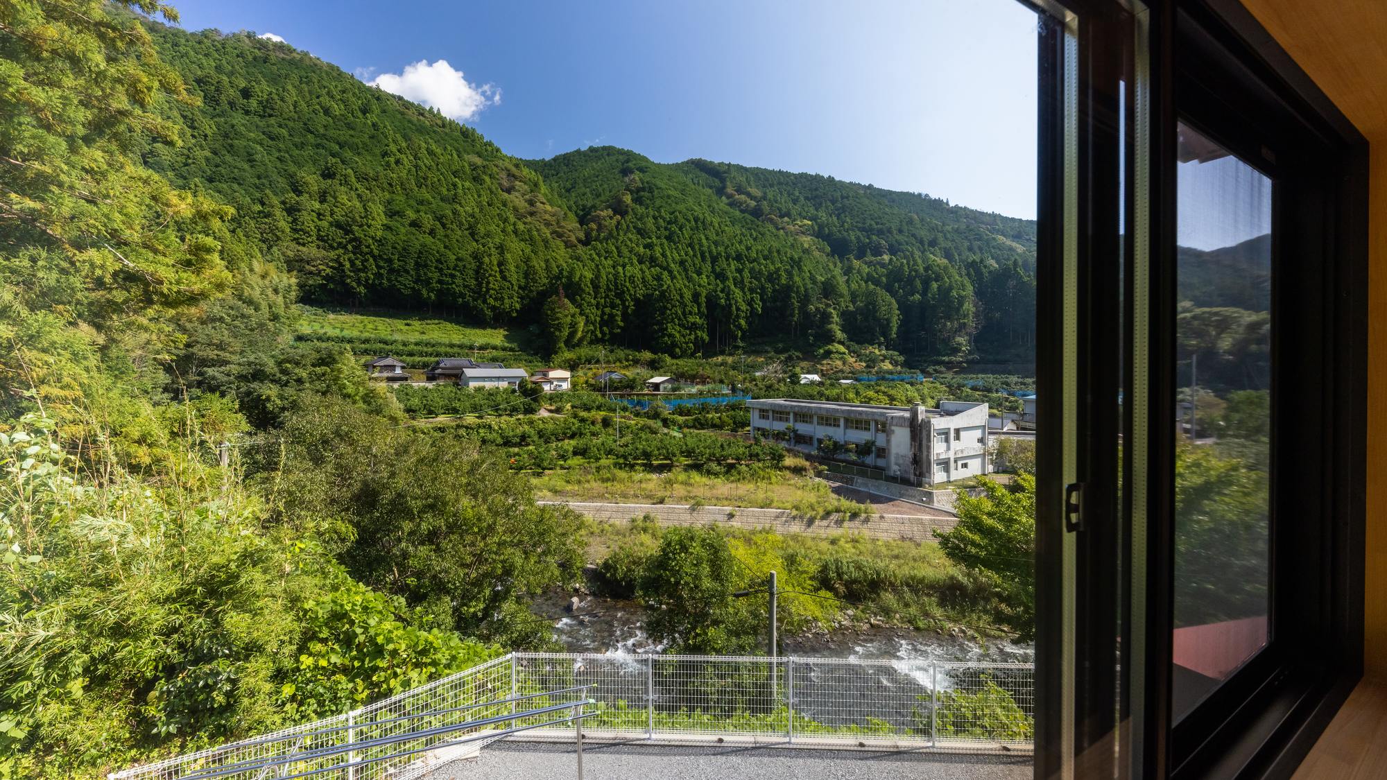 ・【景色】窓越しに広がる、緑豊かな山と澄んだ川の風景。夏は川遊びも楽しめます