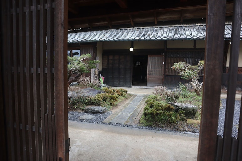 門を開けて、まず正面に見える建物は母屋です。宿はこちらの建物ではありません。案内板を取り付けて...