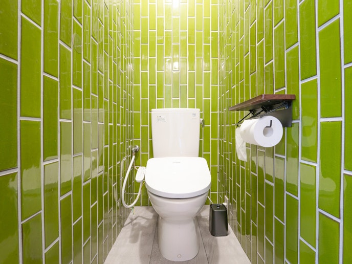 ・【トイレ】温水洗浄便座付き。緑色のタイルの壁が印象的です