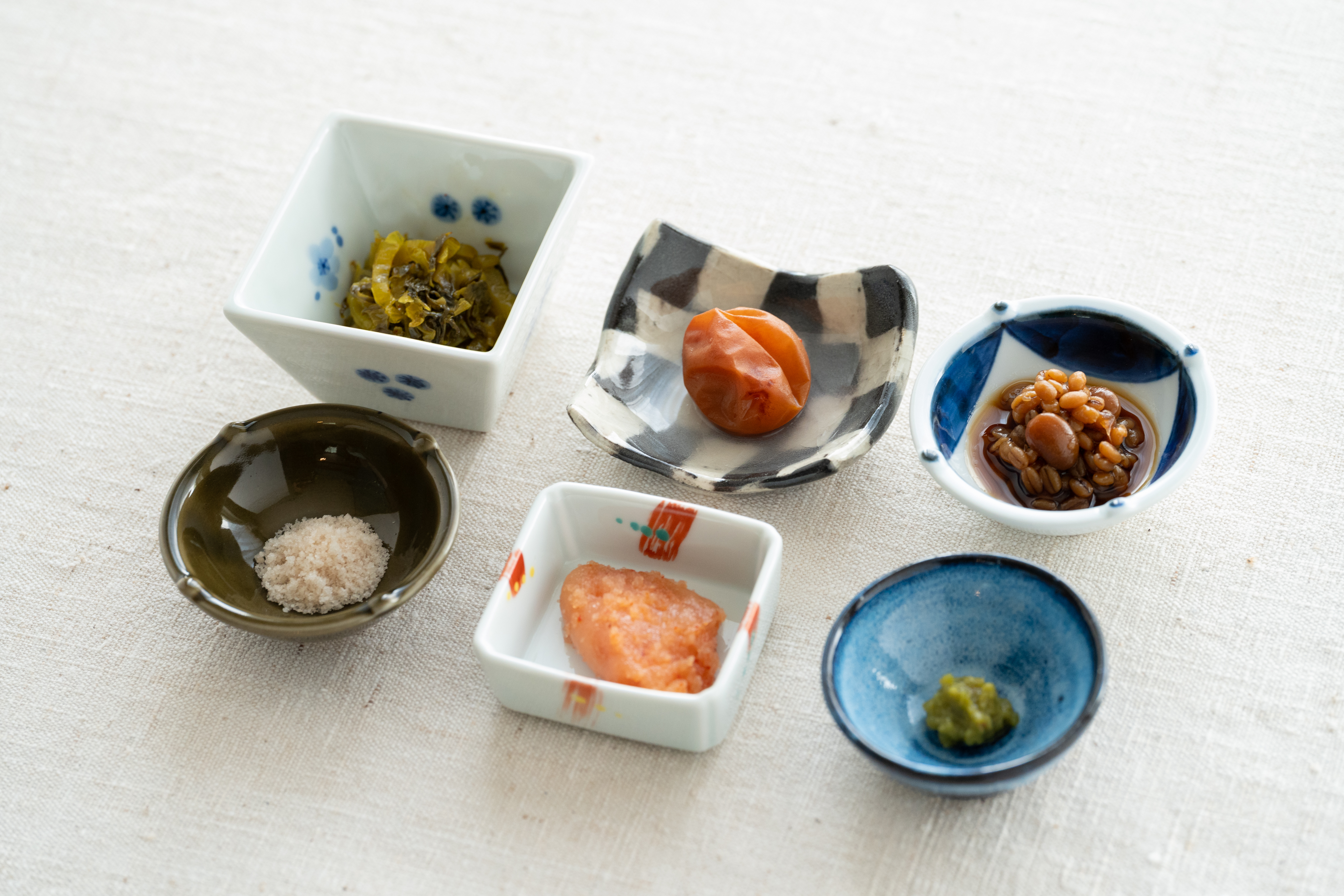 左上から「樋口漬物の辛子高菜」「自家製低塩梅干し」「醤油の実」 左下「対馬の藻塩」「辛子明太子」「南さんの柚子胡椒」 
