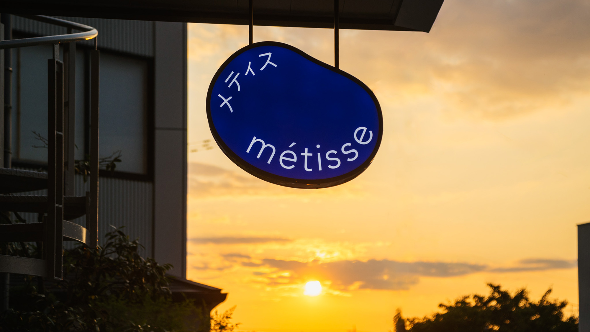 ・【看板】夕焼けに染まるmetisseの看板は、旅の思い出を美しく彩ります