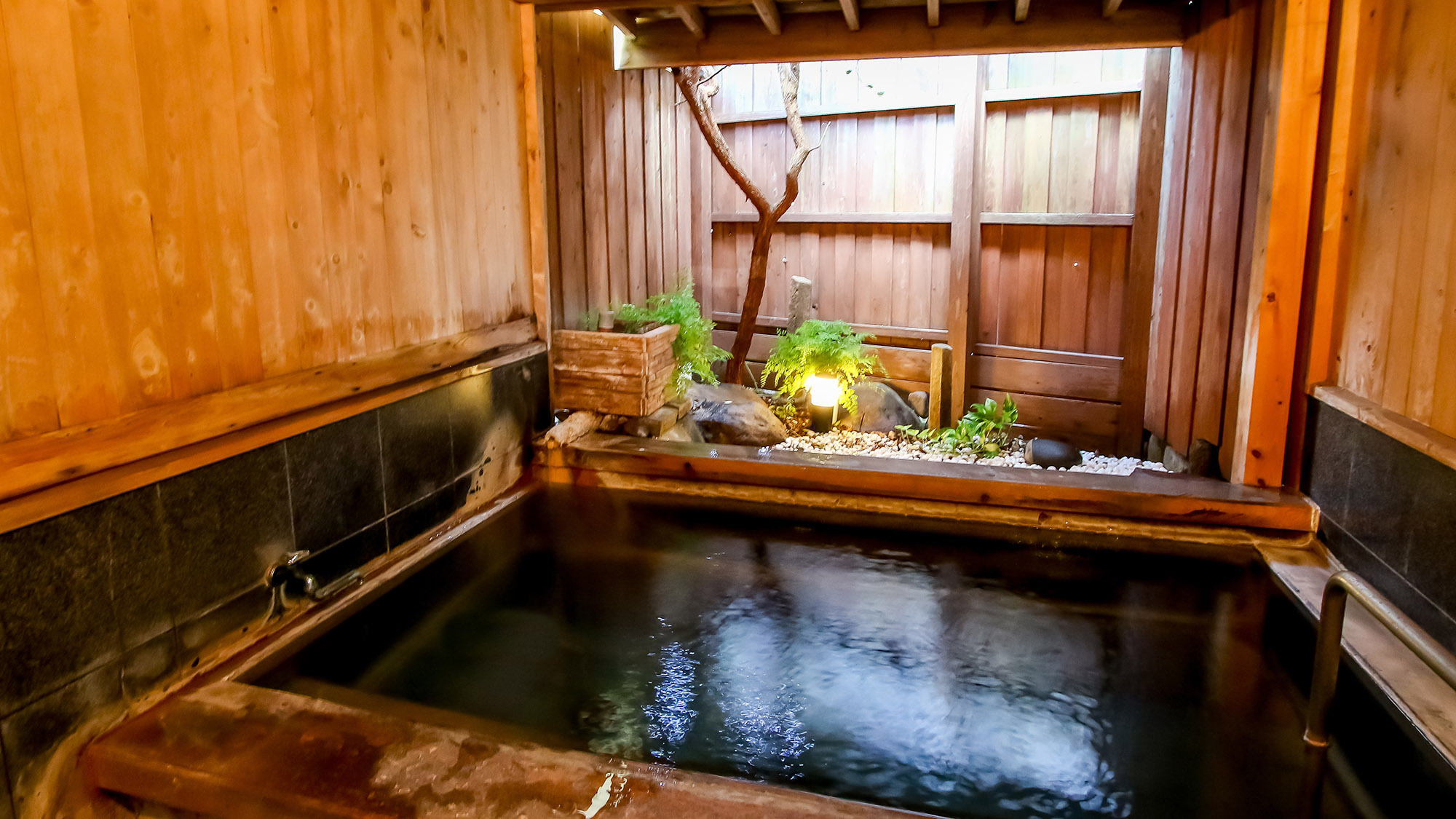 【半露天風呂】ひのきの壁と岩が調和した落ち着きのある湯処。半露天風呂は雨の日でも安心です