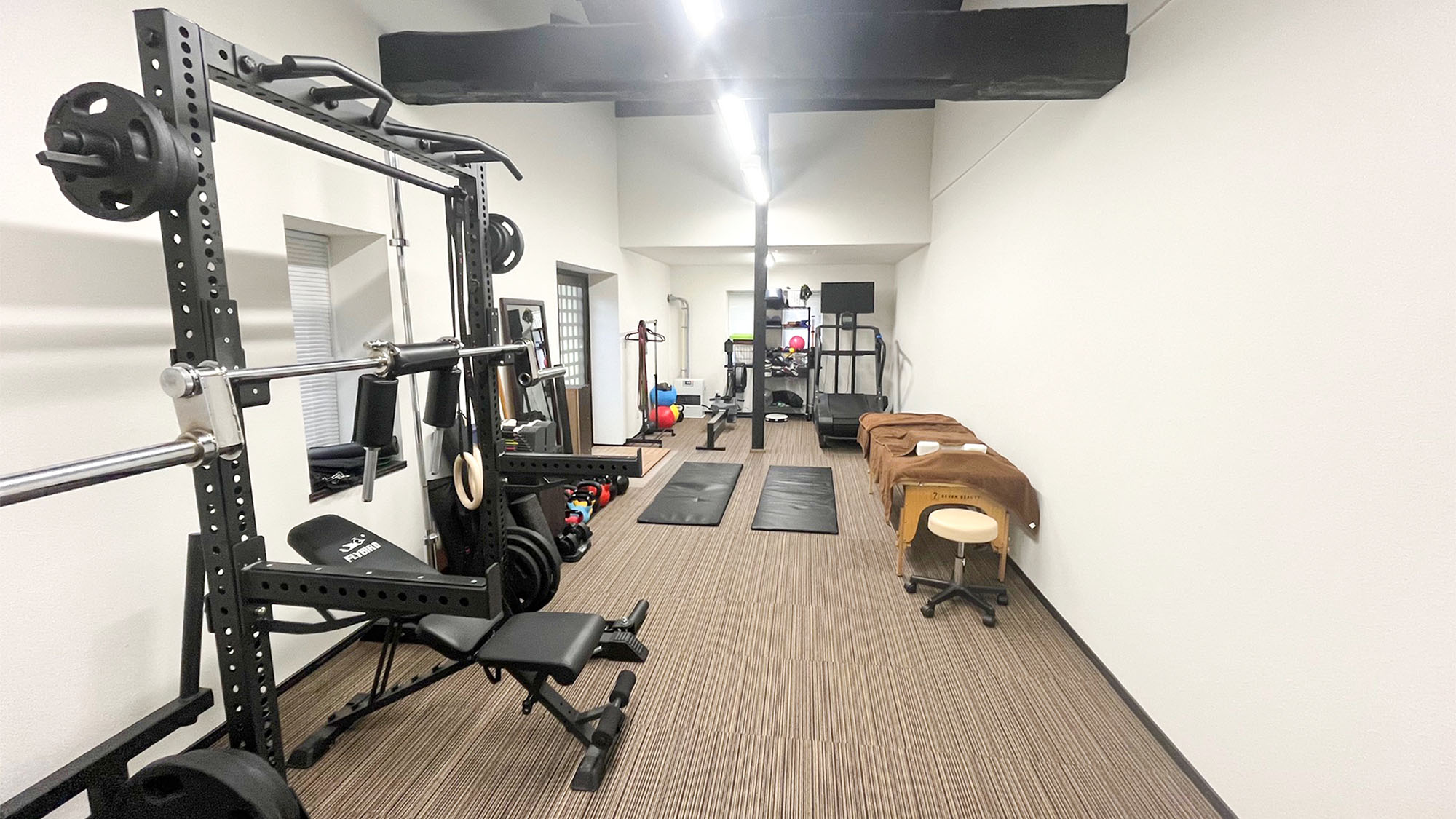 ・【トレーニングルーム】充実したマシンと施術ベッドが並ぶ、清潔で落ち着くパーソナルジム空間。