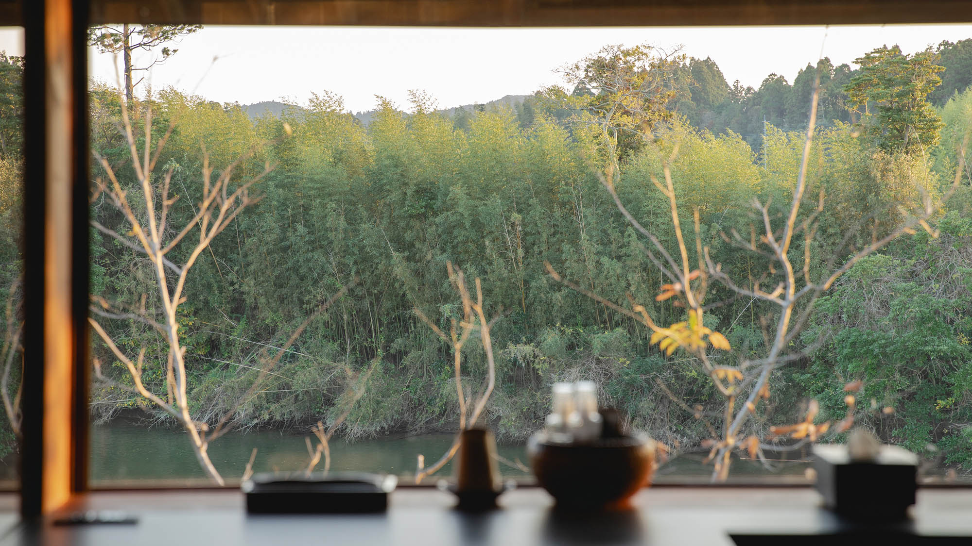 ・【バスルーム】洗面スペースから望む、一面に広がる草木の緑と黄土色の夷隅川