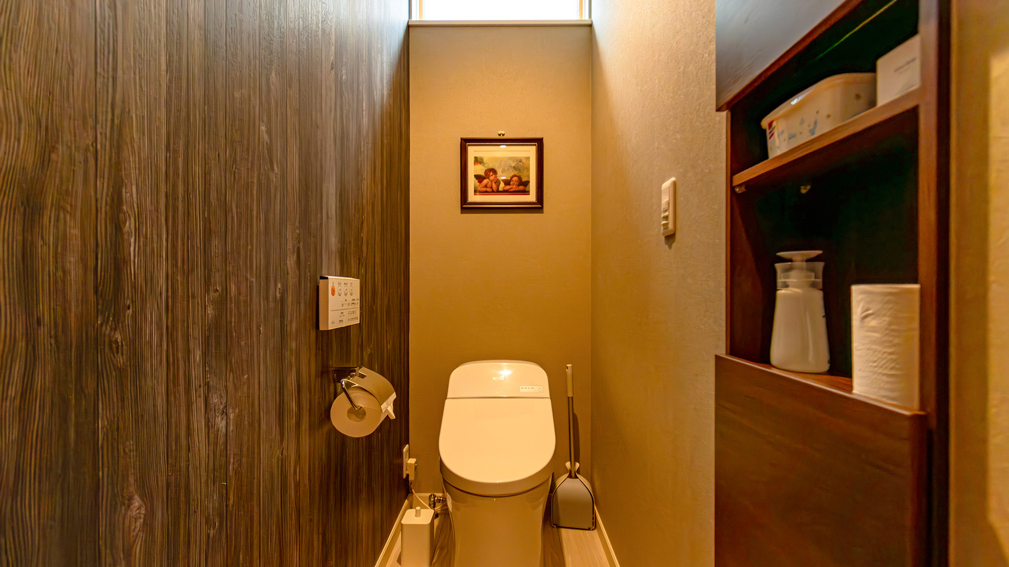 ・【トイレ】温水洗浄便座付き。ウッド調の壁紙と絵画が、落ち着いたトイレ空間を演出