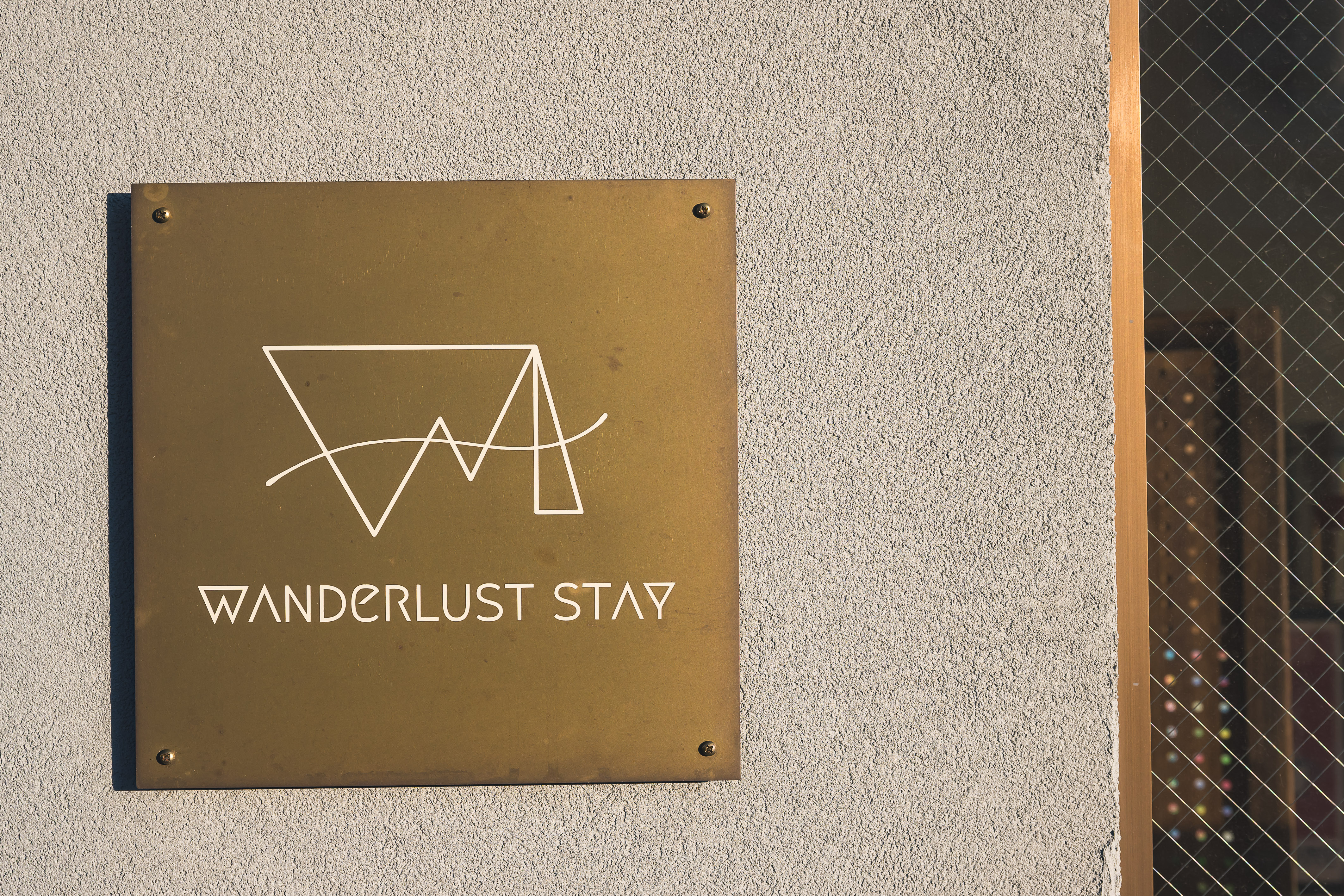 玄関には、真鍮製のWanderlust STAYのロゴが飾られ、皆さまをお迎えします。