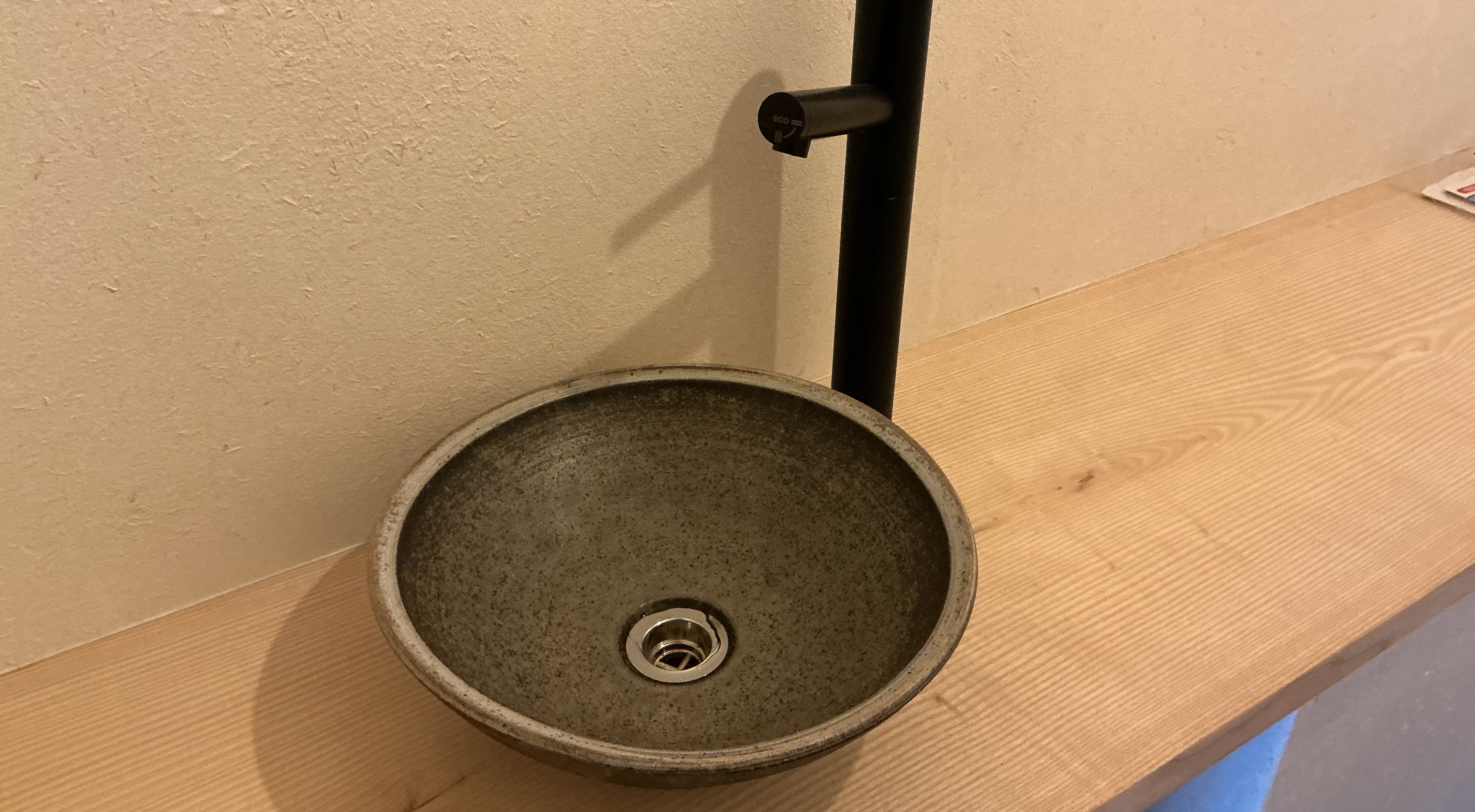【モデレートリトリート】石の質感と木の温もりが調和する、静かなトイレスペース。