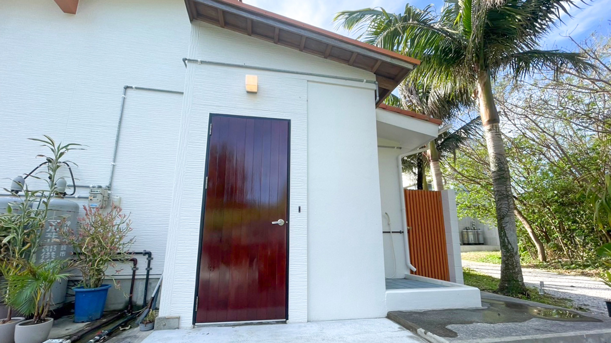 ・【外観】沖縄の風情を感じられる白壁・赤瓦のゲストハウス。ヤシの木が南国気分を盛り上げます