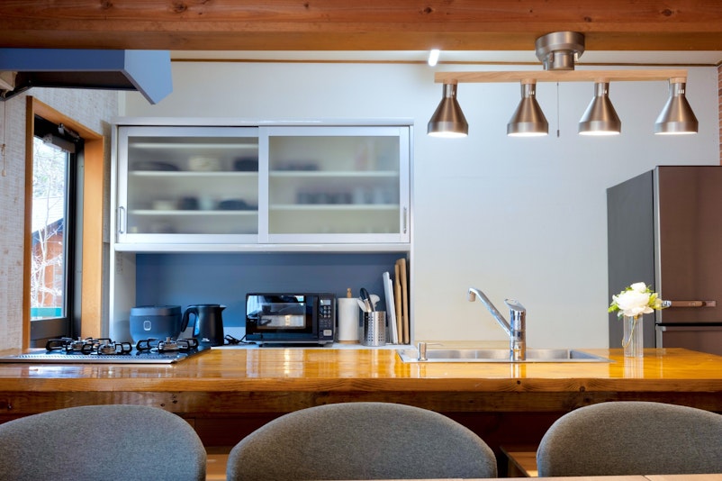 ダイニングからキッチンを写した写真です。ライトや冷蔵庫はメタリック調として、デザインにもこだわ...