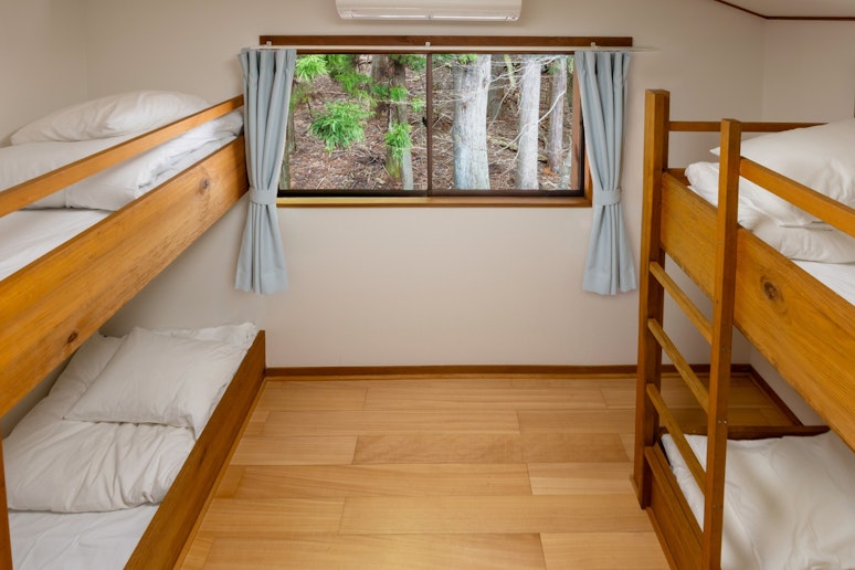2階にある、2段ベッド2台のお部屋の雰囲気が分かる写真です。窓から見える森の景色も魅力の一つ。