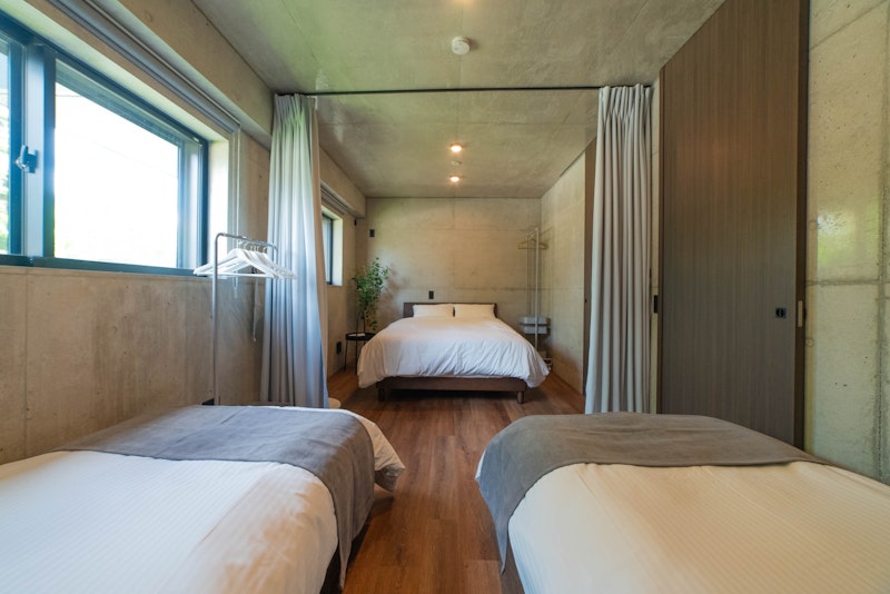 1階の間仕切れる寝室は、一方にダブルベッドを1台、もう一方にシングルベッドを2台配置