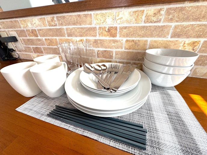 レンガ調の壁を背景に、シンプルかつ上品な食器類が整然と並ぶ朝食スペース。カップやボウル、プレー...