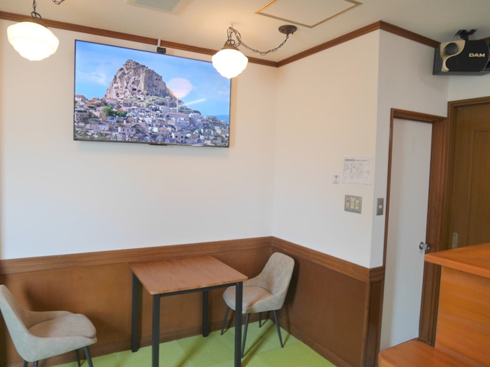 1階のカラオケルームです。 テーブルと一人掛け椅子が2脚ございます。