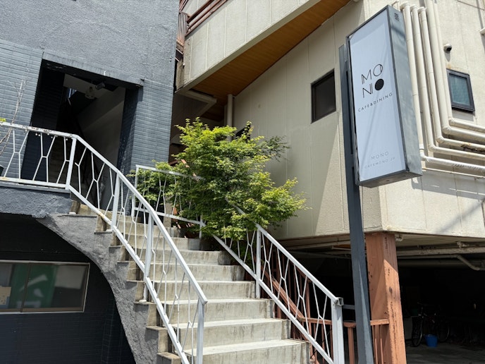 エレガントな外階段と入口付近のガーデンスペース。緑の植栽とスタイリッシュな建物の外観が調和し、...