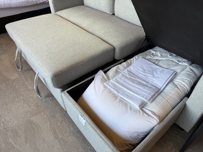 収納式のソファベッドの内部に寝具やリネン類が整然と収納されており、必要に応じてすぐに睡眠スペー...