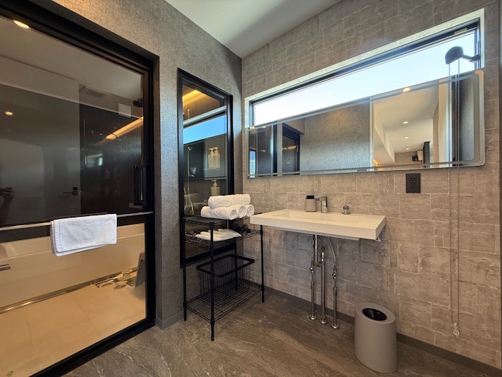 洗練されたデザインのバスルームです。壁には落ち着いた色調のタイルが使用されており、清潔感のある...