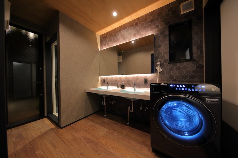 デザイン性の高い洗面所は、木目調の天井とフローリング、間接照明で心地よい空間を演出しています。...