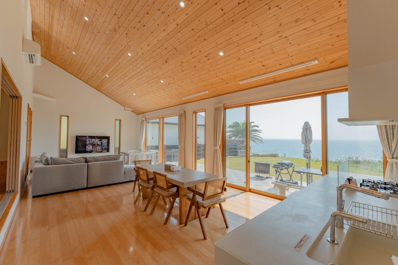 木の温もりを感じる高天井のリビングダイニング。窓の先には美しい海景が広がり、開放的なひとときを...