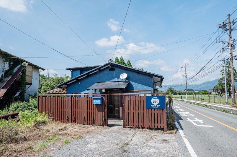 木製の門扉と青い外壁が特徴的な建物。