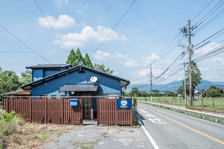 青い外壁と木製ゲートが特徴的な建物。