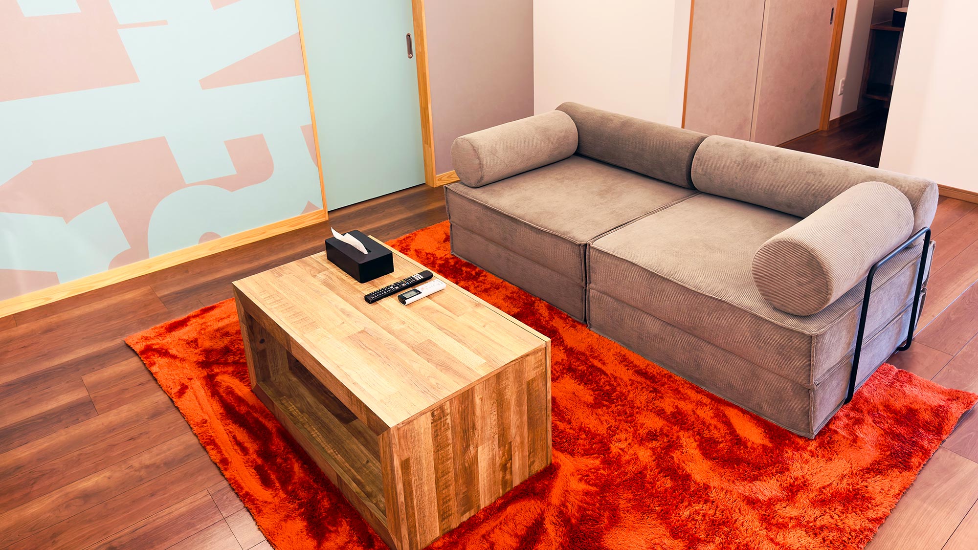 ・【2Fリビング】壁面のアートやオレンジ色のカーペットがスタイリッシュな空間