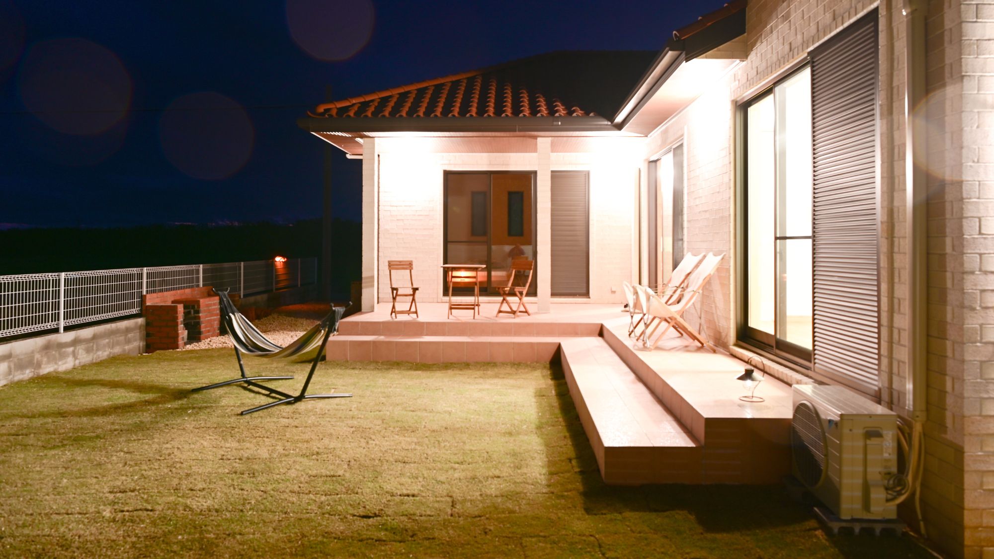 広い庭とウッドデッキ付きの夜の外観。