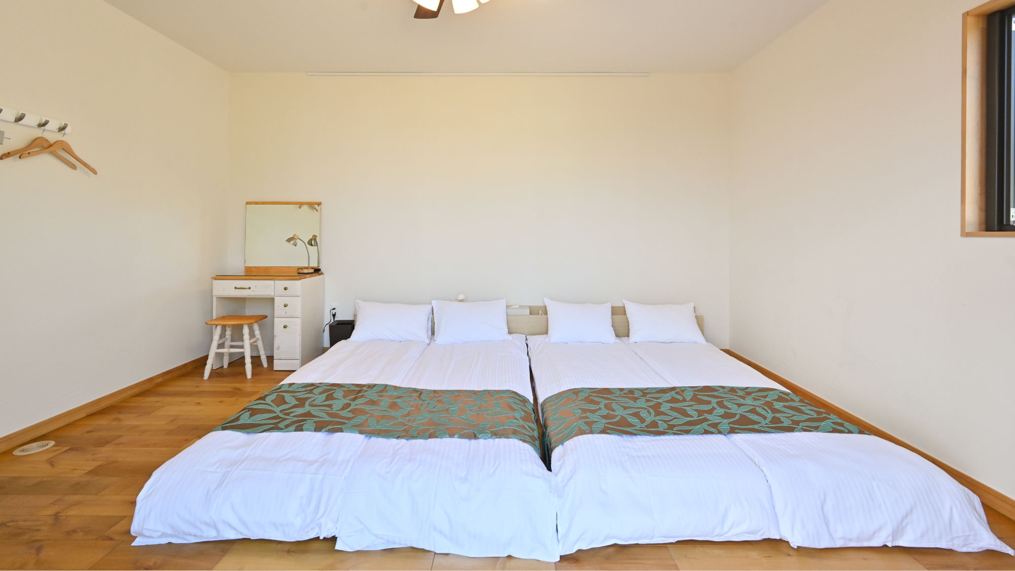 ダブルベッドが並ぶ広々とした寝室。快適な空間。