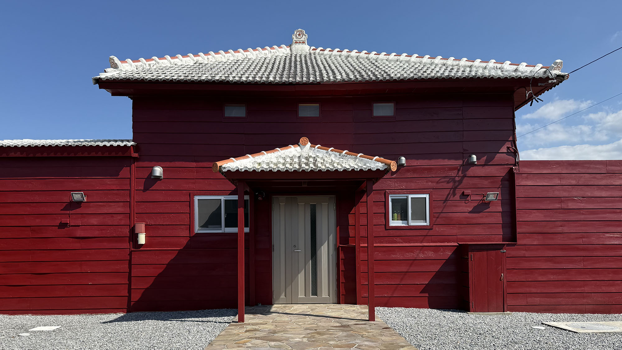 ・【外観】今帰仁エリアに立つ愛山荘　沖縄の空の青と紅色のコントラストをお楽しみください