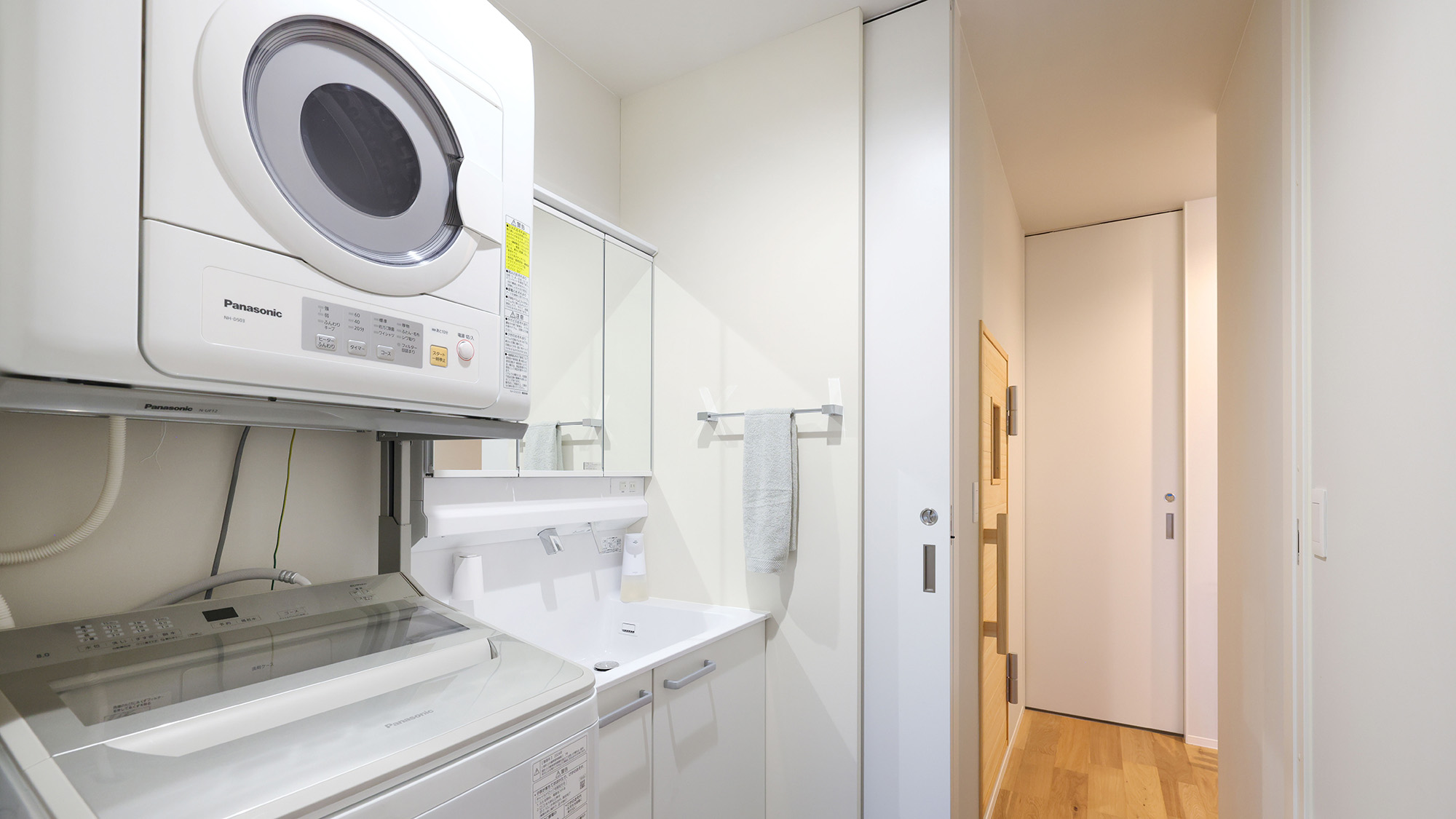 ・【A棟／洗面所】洗面台横には洗濯機・乾燥機を完備。少ない荷物でも安心してご宿泊いただけます