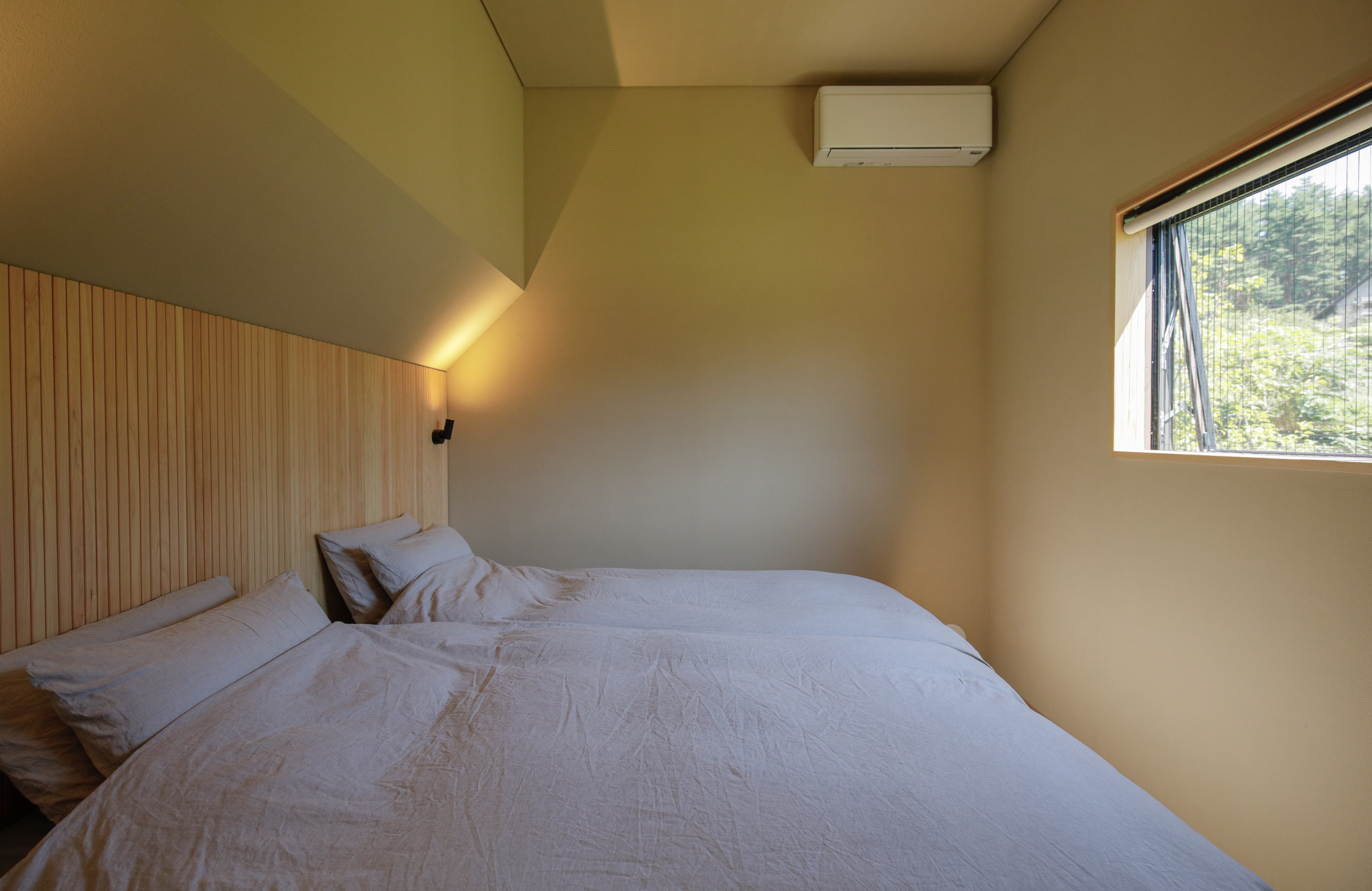 漆喰や天然の木に囲まれた柔らかい雰囲気のツインタイプのベッドルーム