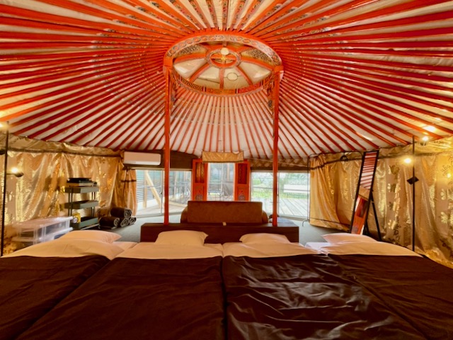 ゲルの内部は、自然素材に囲まれたやさしい空間。定員４名までゆったりとお過ごしいただけるよう、ソファとマットレスを備え、グループやご家族での滞在にも最適です。間接照明があたたかく室内を照らし、夜の時間も心地よくリラックス。エアコンも完備しているため、夏も冬も快適にお過ごしいただけます。天井の美しい梁や丸い造りは、モンゴルの伝統の特別な空間。非日常を味わいながら、森の静けさと共にくつろぎのひとときをお楽しみください。
