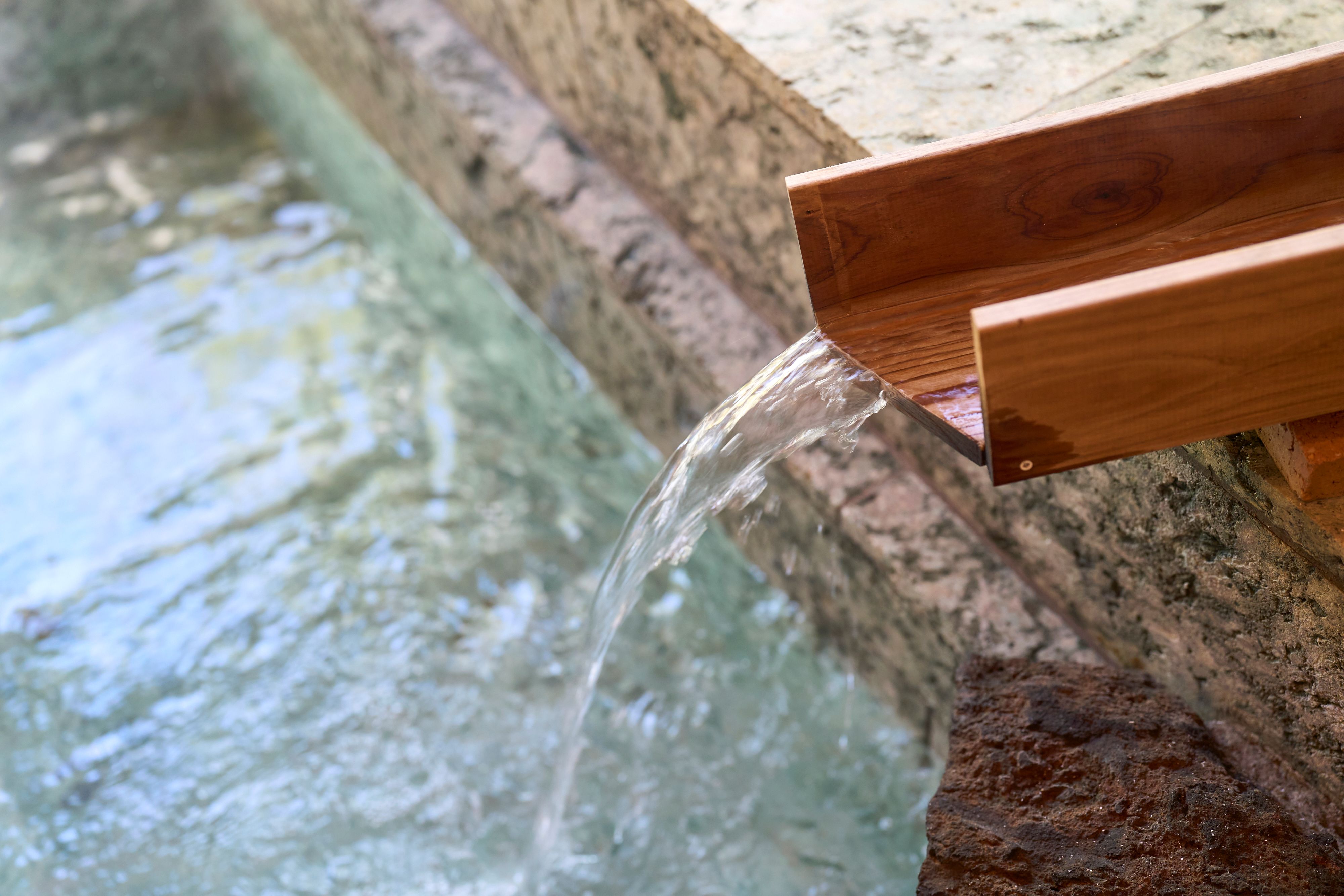 【温泉】木製の湯口から注がれる温泉。心まで癒される贅沢なひととき。