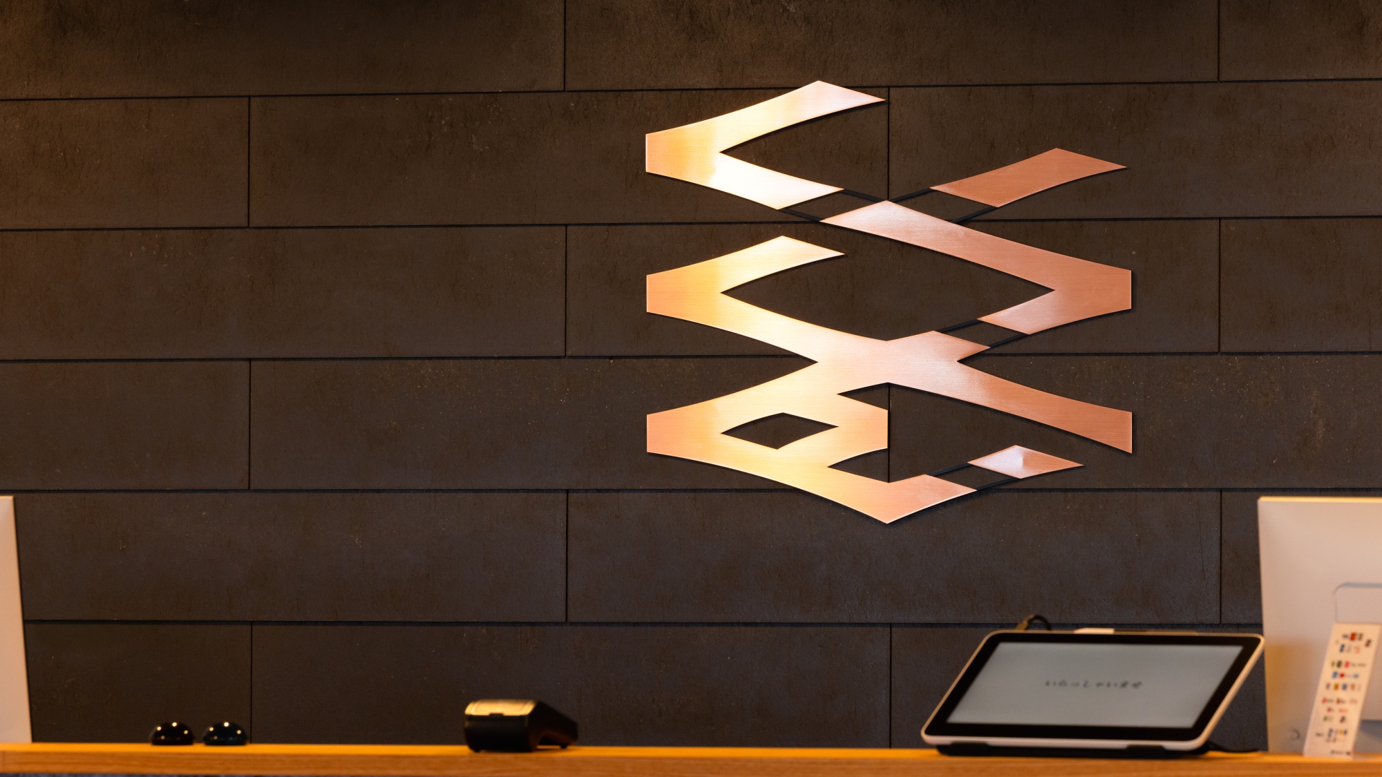 【フロント】宿のコンセプト「紡ぐ」「紡いでゆく」をイメージしたロゴで皆様をお出迎え。