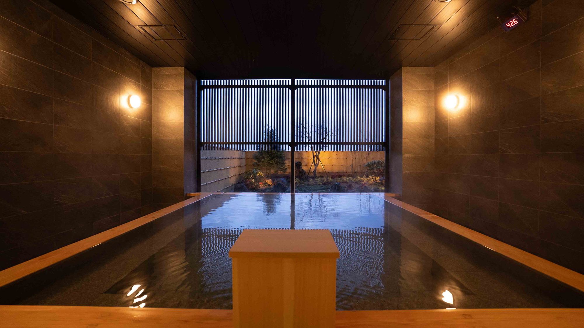 【温泉大浴場】庭園眺望の大浴場。雨や雪の日でもご利用いただける半露天仕様となっております。