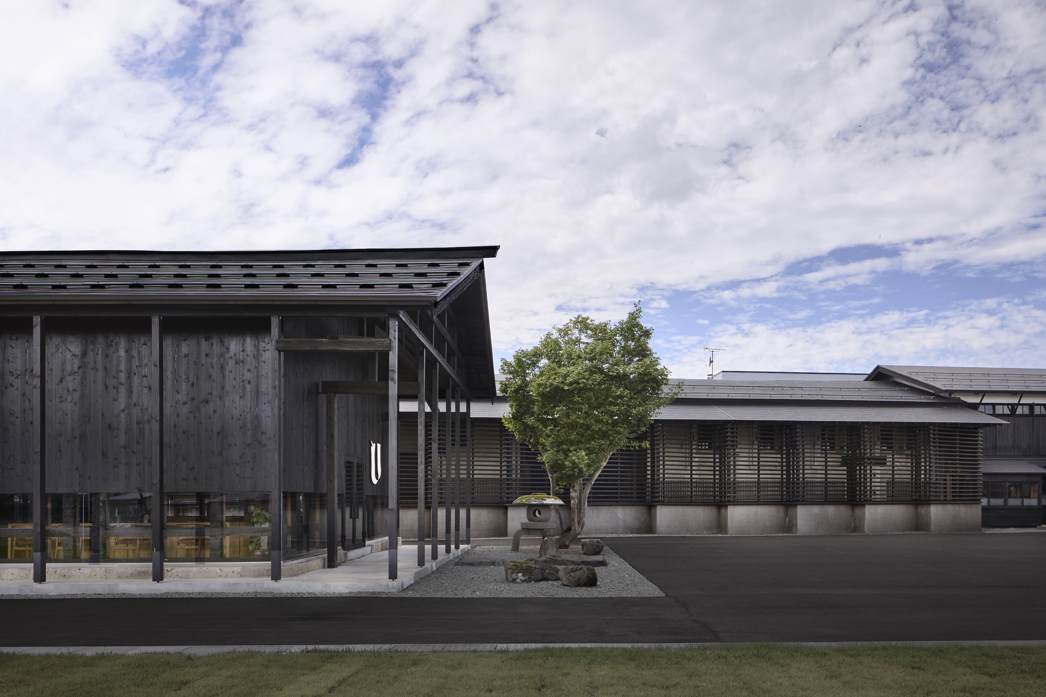 Facade｜ラウンジ棟の奥にある3棟の内蔵を活用した宿泊/サウナ棟には永沢碧衣氏の大型アート作品を