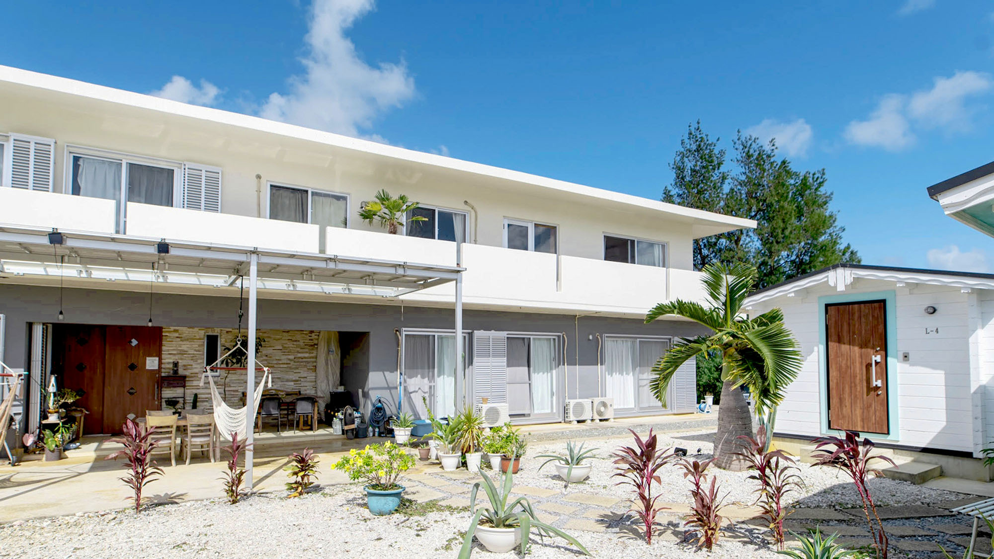 ・【外観】陽光きらめく白い外観。南国の緑に包まれた、心安らぐゲストハウス