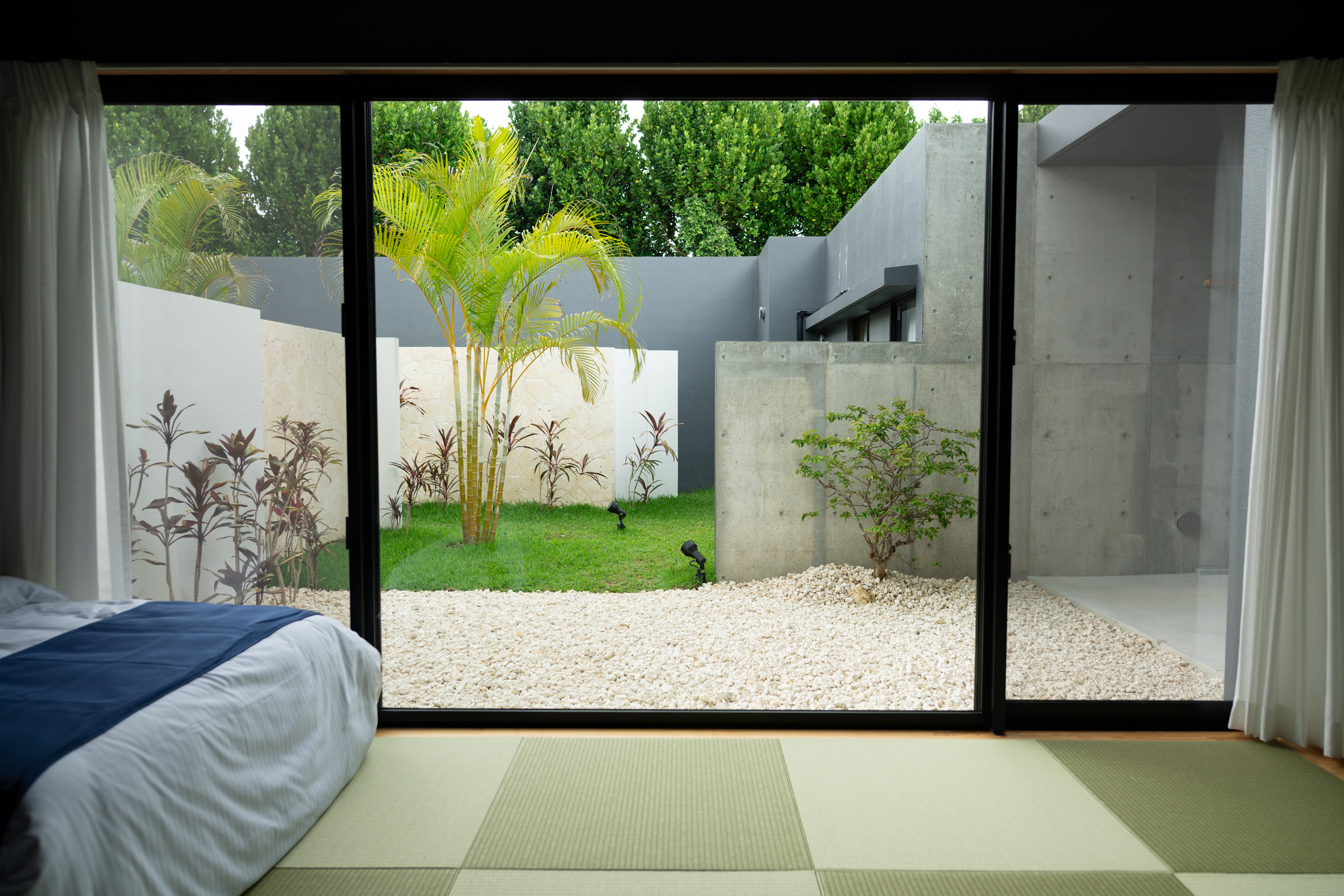 【和】お部屋から沖縄らしいアレカヤシやセンネンボクが彩る中庭を望む