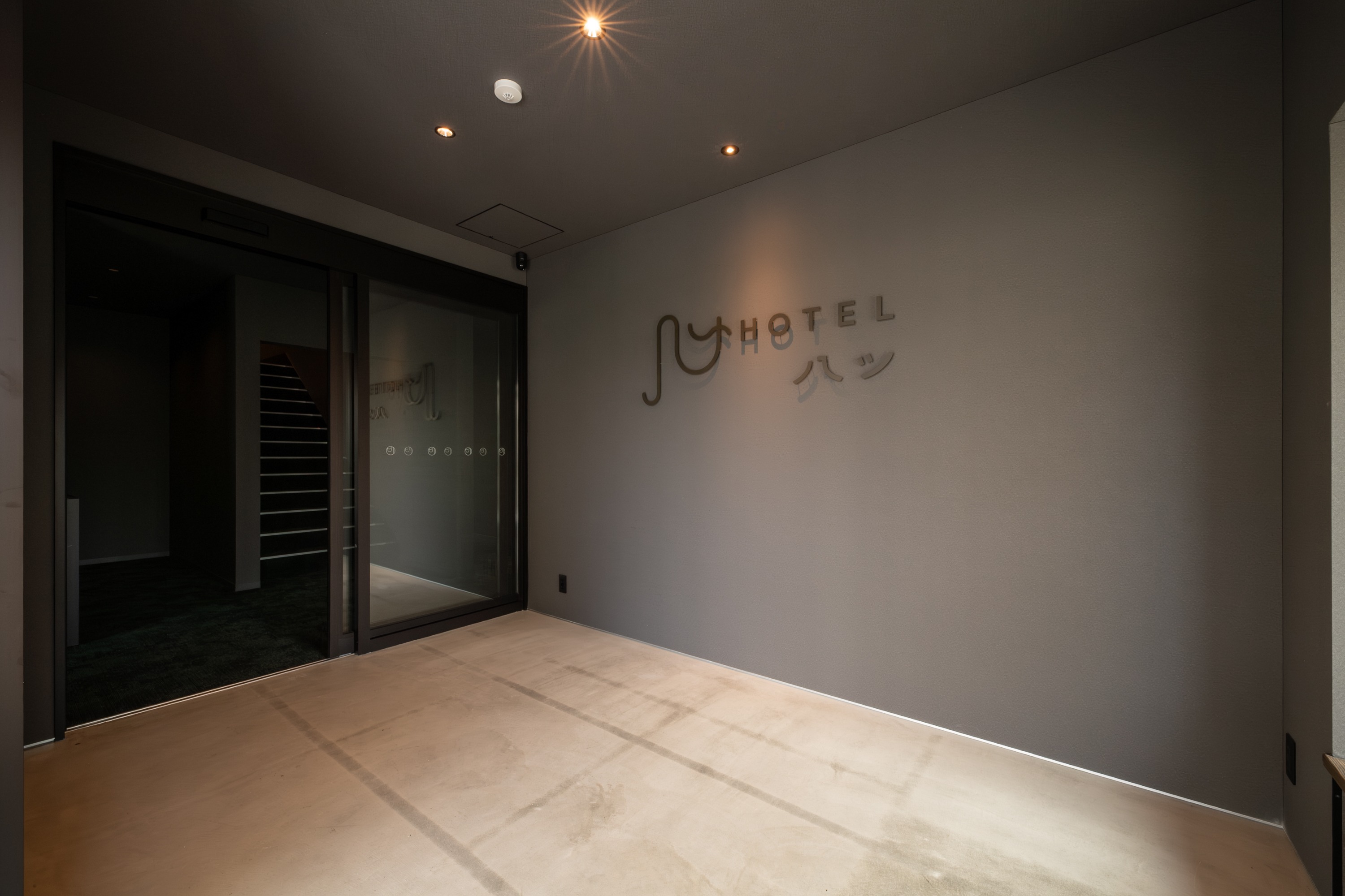 観光で訪れるお客様を迎えるホテル八ツのエントランスは、洗練されたデザインと自然光が生み出す温かみが特徴です。旅の始まりには「ようこそ」、観光から戻ったときには「おかえりなさい」と、何度でも気持ちよく迎えてくれる場所。シンプルながら上質な雰囲気が安心感を与え、チェックインの瞬間から滞在の楽しみを広げます。街と旅人を結ぶ、心地よい出迎えの入口です。