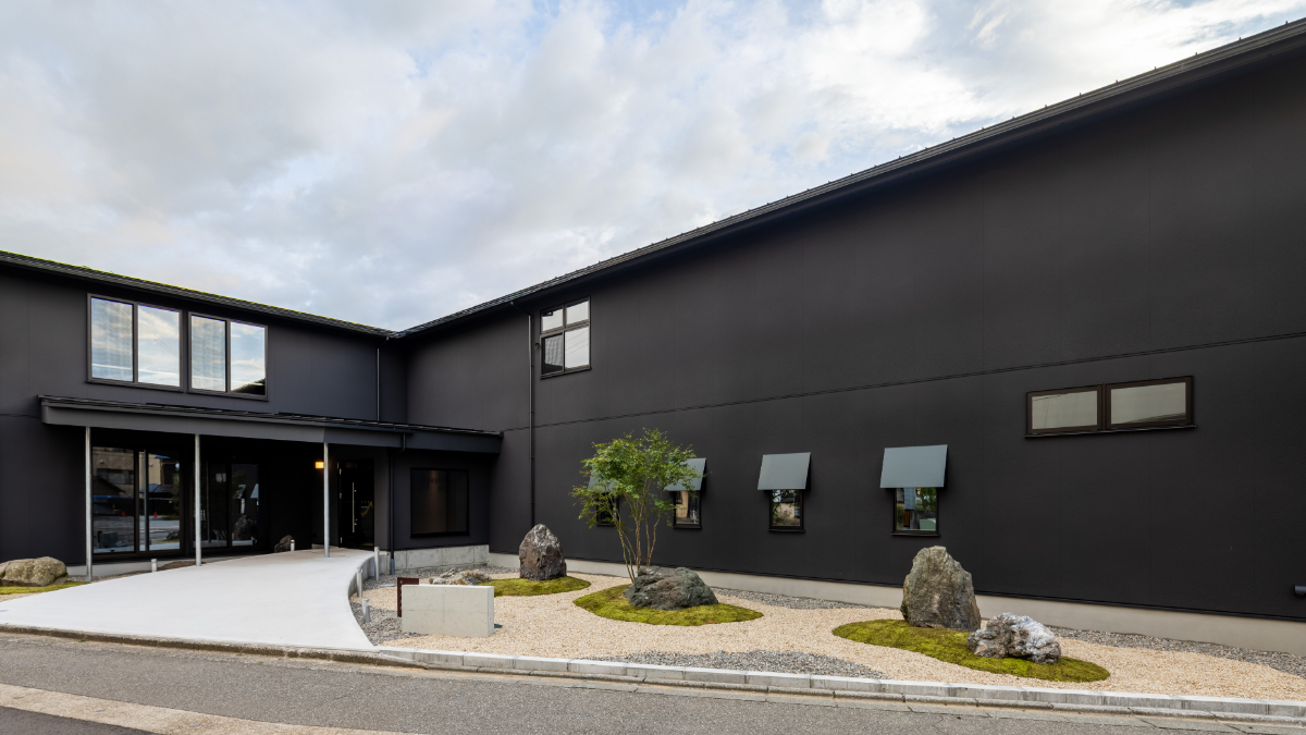 重厚感のある黒壁が印象的なホテル八ツの外観は、シンプルでありながら独自の存在感を放っています。直線的な建築デザインは、無駄をそぎ落とした美しさを表現し、訪れる人に落ち着きと安心感を与えます。外観の色合いは周囲の自然や街並みに調和し、時間帯や季節によって異なる表情を見せます。シックなデザインの中に漂う上質な雰囲気は、日常を忘れて特別なひとときを過ごすための空間として、ゲストの期待を高めることでしょう。  