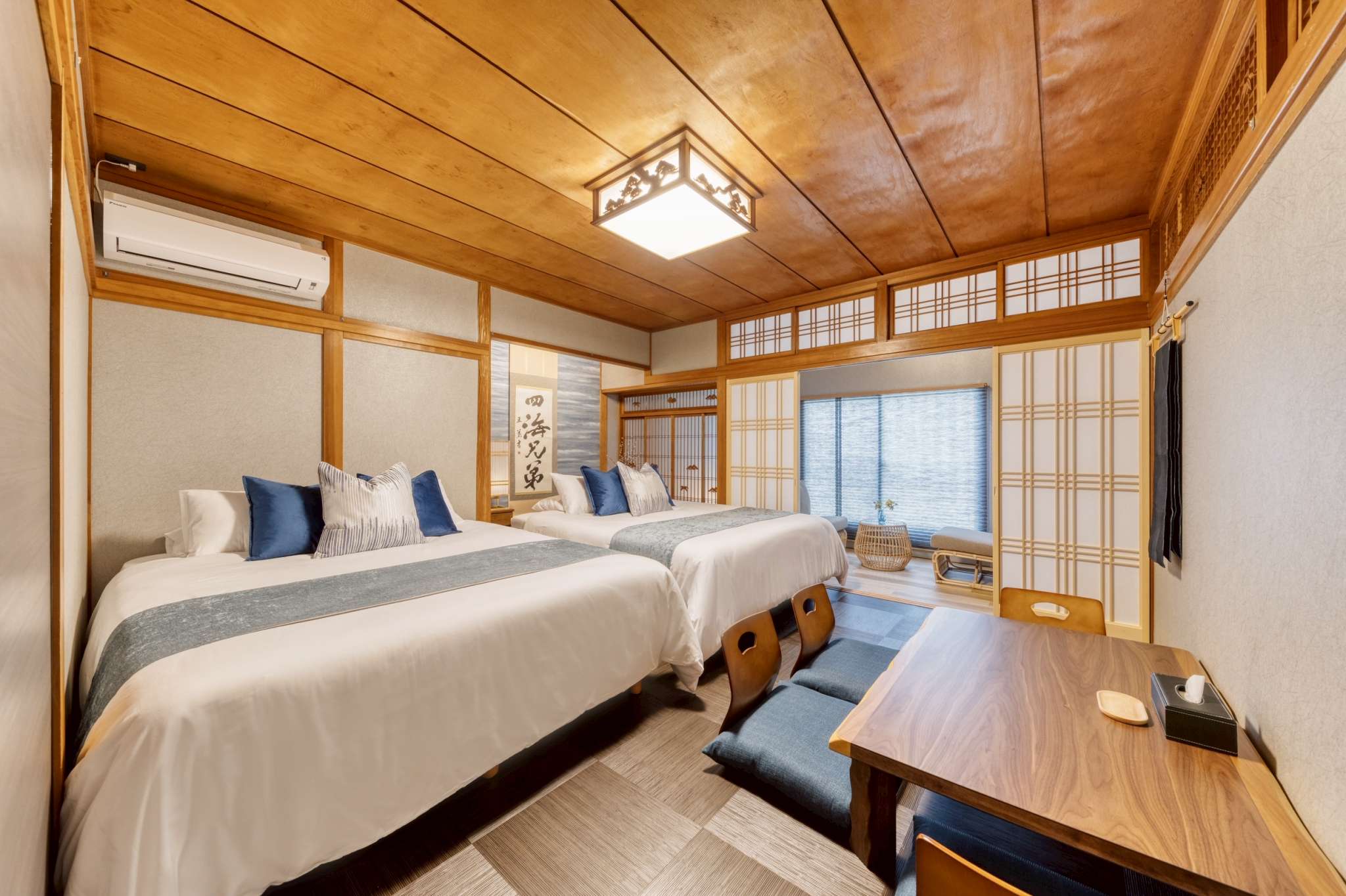 障子や木のぬくもりを感じる内装にベッドを配置し、快適さと和の趣を兼ね備えています。 小上がりスペースには座卓と座椅子があり、腰を下ろしてくつろいだり、食事や読書を楽しんだりできます。