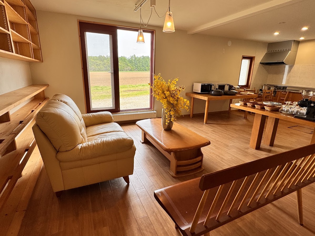 窓から差し込む柔らかな自然光に包まれた、薫風舎の共有ダイニングスペース。木の温もりを感じる家具と、季節の花が彩るテーブルが、訪れる人々に穏やかなひとときを届けます。キッチン家電も揃い、セルフスタイルでの調理や軽食も可能。朝のコーヒーから夕暮れの語らいまで、ここは滞在者同士の心がふっとほどける場所です。