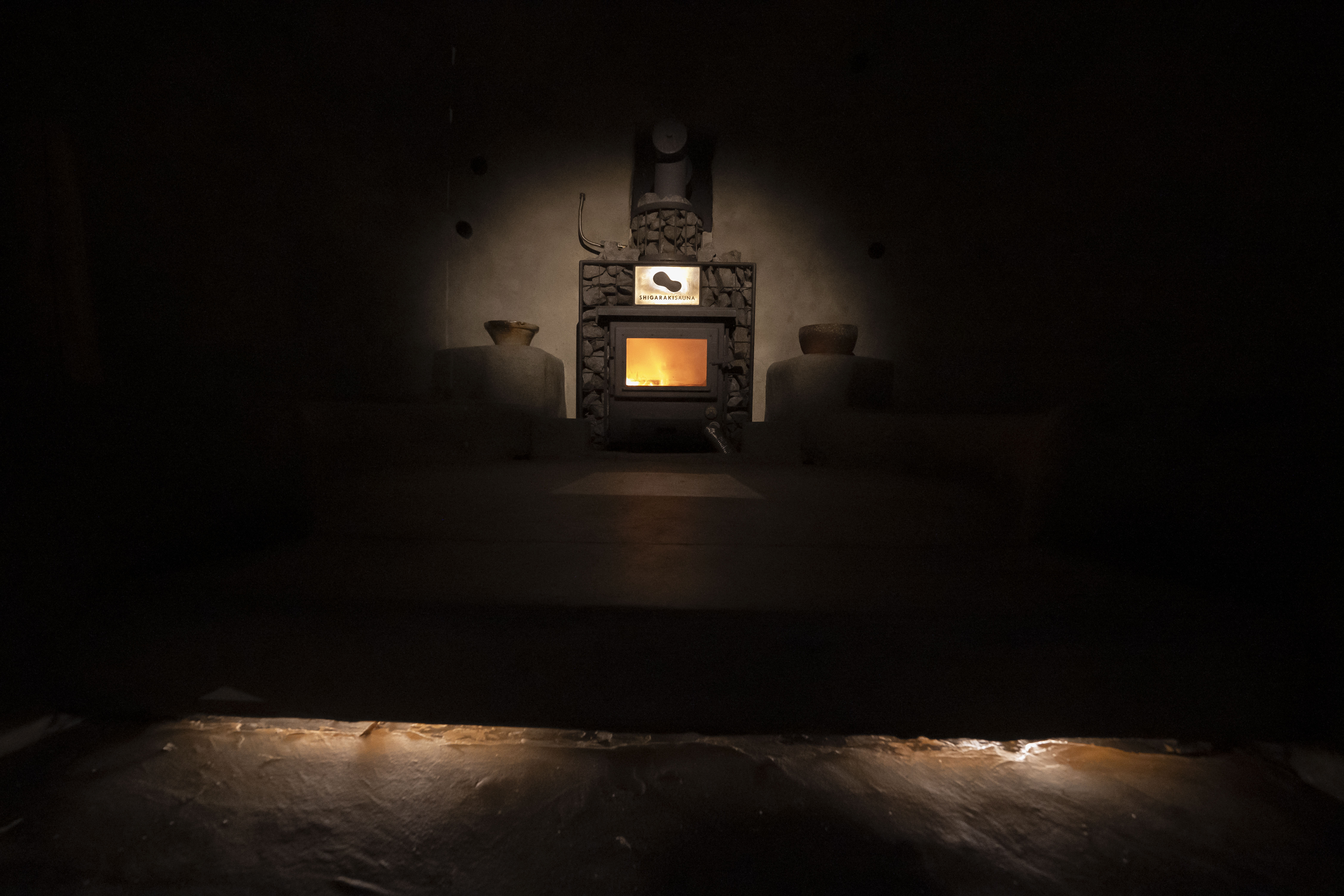 薪ストーブの炎ゆらめくサウナ室
